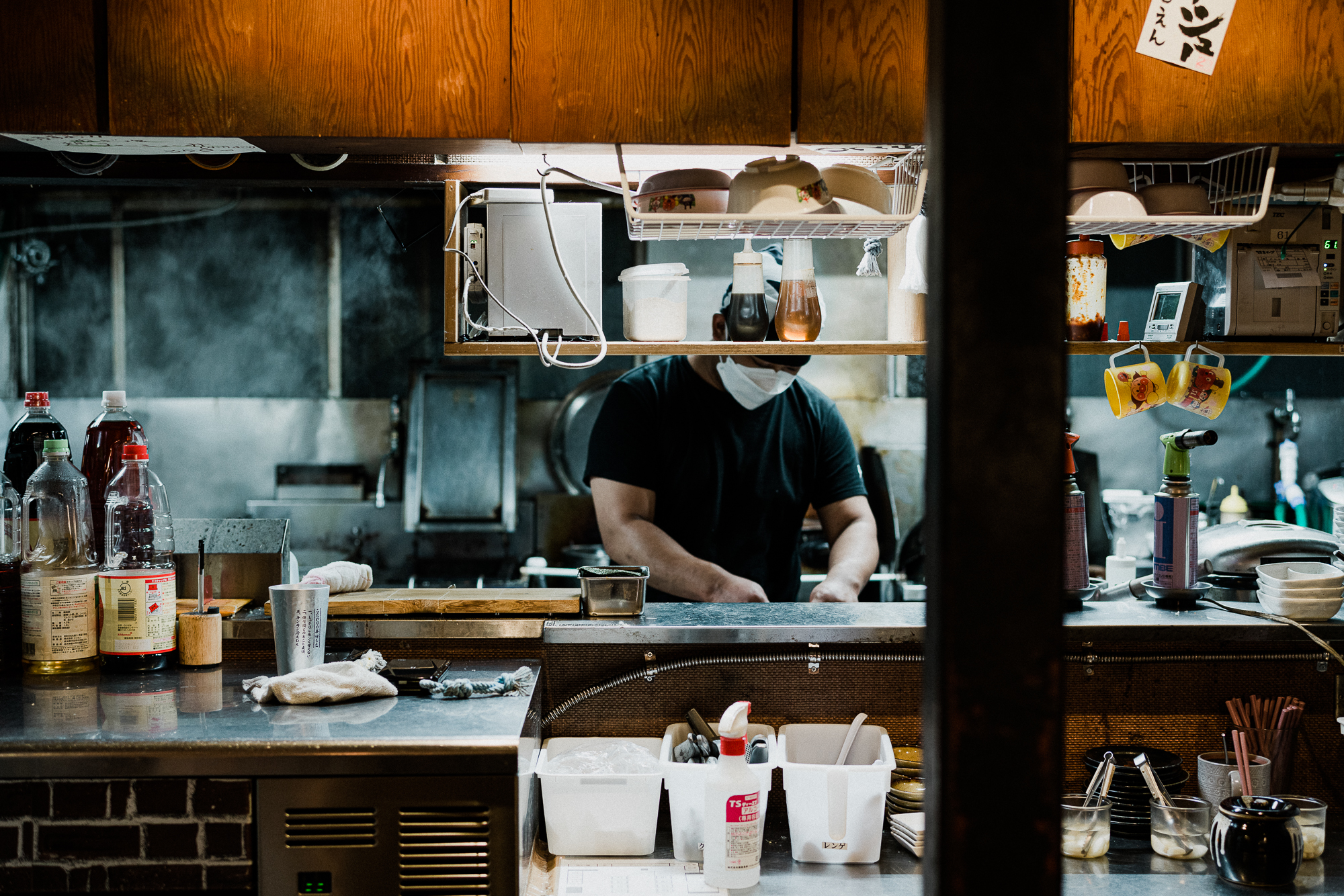 Barista pouring steamed milk into a cup of espresso to create latte art, with coffee equipment and cups visible in the softly lit café environment